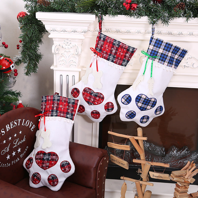 Three Christmas stockings with plaid patterns hanging by a fireplace.