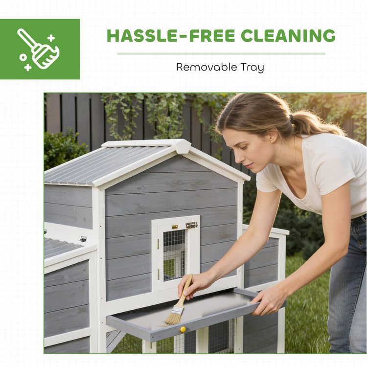 Woman cleaning a gray chicken coop with a removable tray feature.