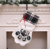 White Christmas stocking with plaid accents hanging on a fireplace mantle.