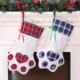 Two Christmas stockings with paw print designs hanging on a fireplace mantle.