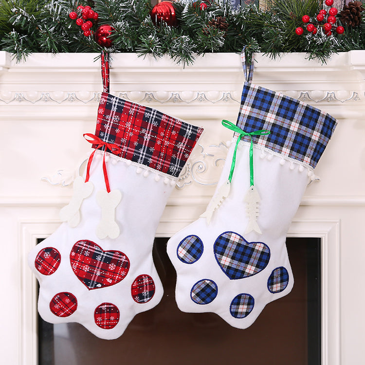 Two Christmas stockings with paw print designs hanging on a fireplace mantle.