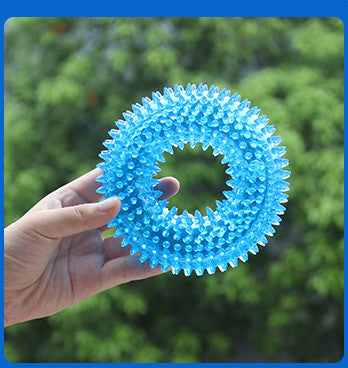 Hand holding a blue textured ball against a green outdoor background