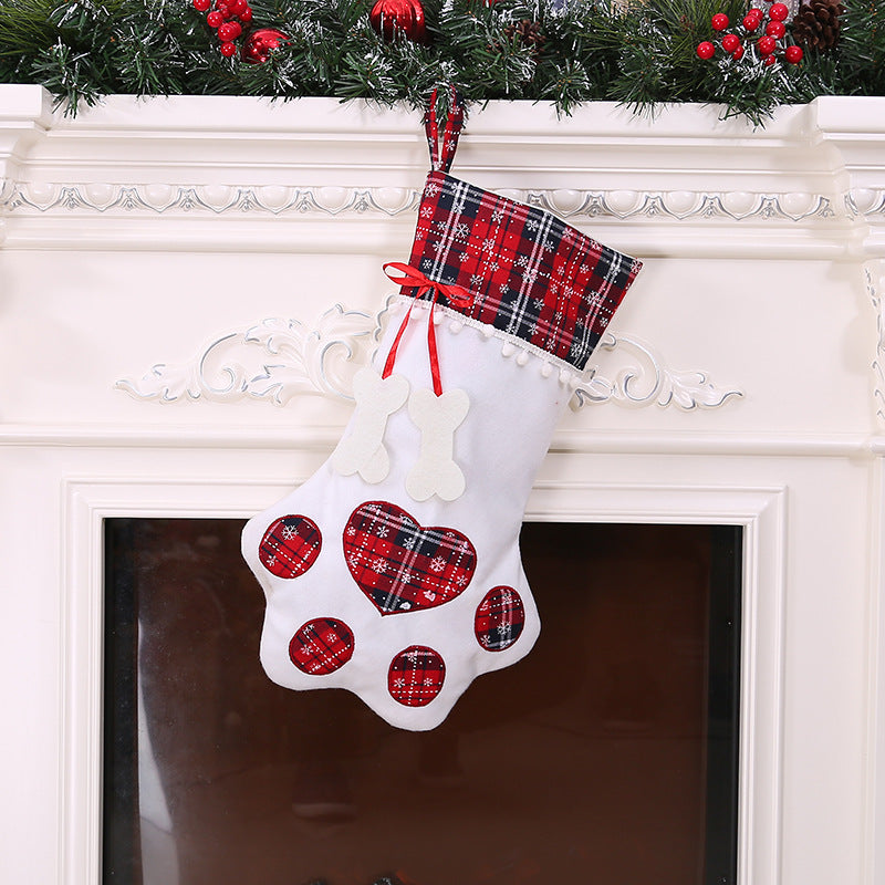 White Christmas stocking with red heart patterns and plaid top hanging on a fireplace.