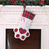 White Christmas stocking with red heart patterns and plaid top hanging on a fireplace.