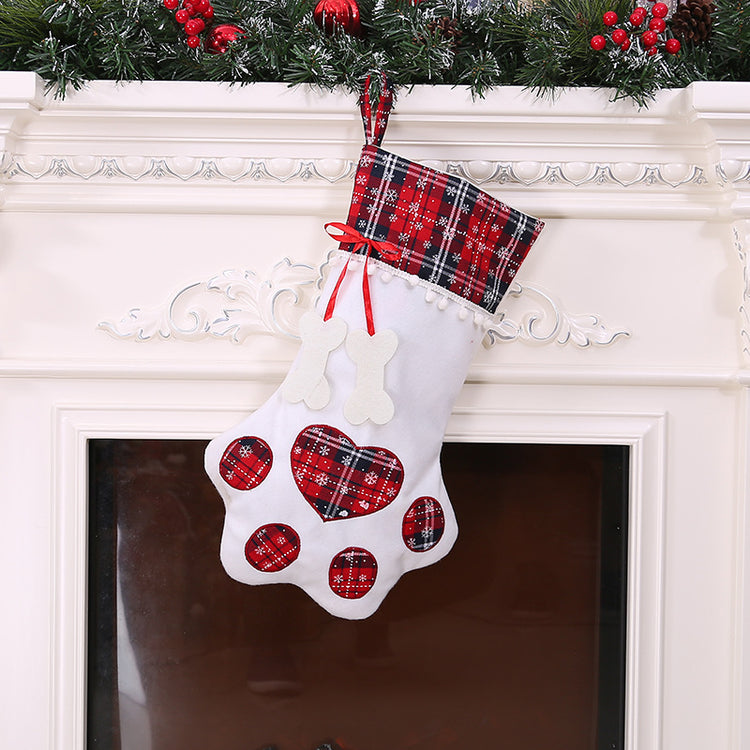 White Christmas stocking with red heart patterns and plaid top hanging on a fireplace.