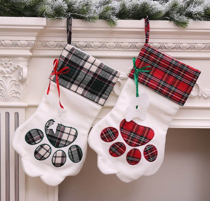 Two plaid paw-shaped Christmas stockings hanging on a fireplace mantle.
