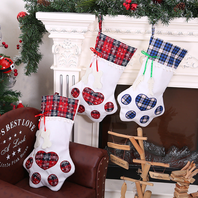 Three Christmas stockings with plaid patterns hanging by a fireplace.