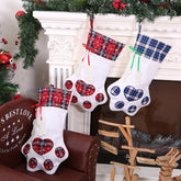Three Christmas stockings with plaid patterns hanging by a fireplace.
