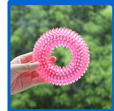 Pink textured ball held by a hand with a blurred green background