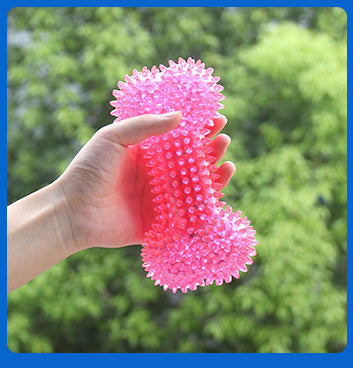 Pink textured ball held in a hand with a blurred green outdoor background